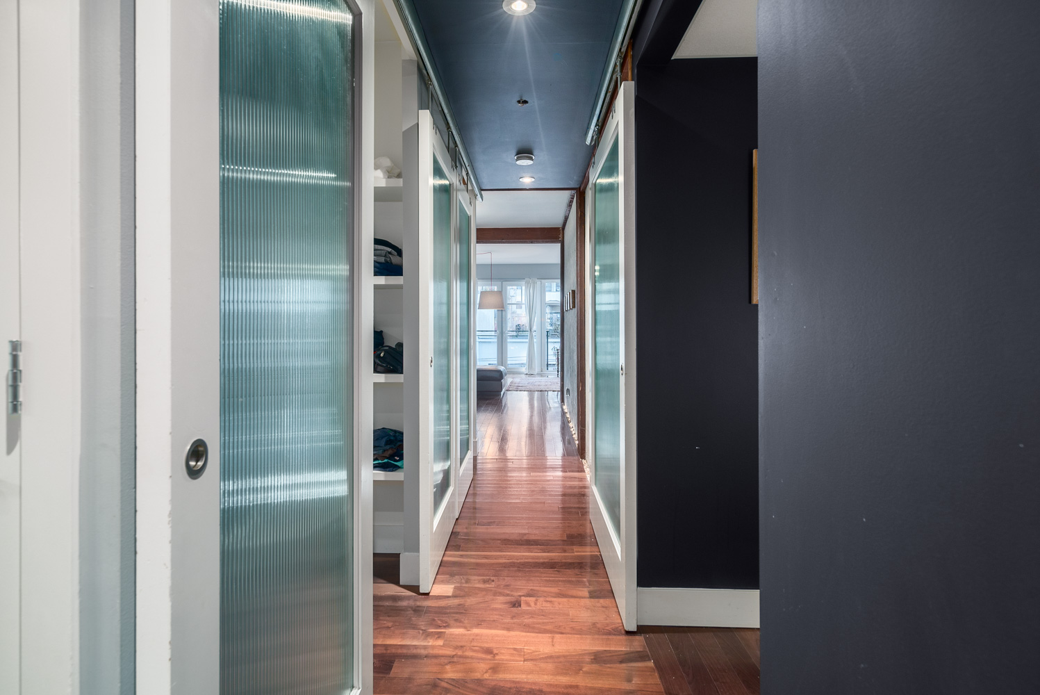 Alluring hallway reveals rustic style barn doors, concrete walls set off with rich walnut floors